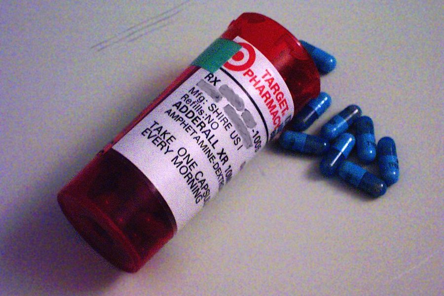 A pharmacy prescription bottle of Adderall XR 10 mg with blue capsules